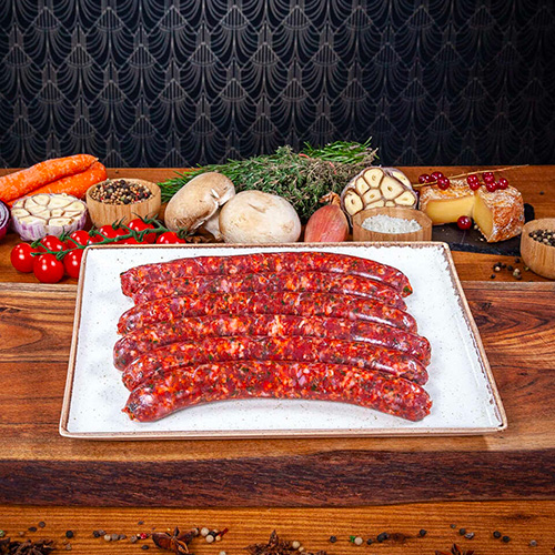 5 merguez artisanales crues présentées dans une assiette