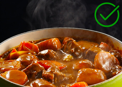 De la viande de boeuf en morceau en train de mijoter dans une cocotte avec des carottes