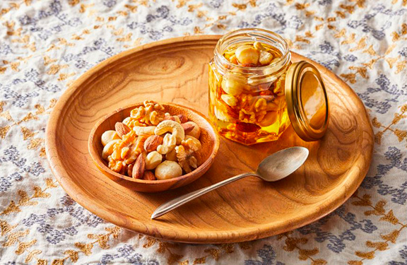 des fruits secs et un pot de miel sur une assiette en bois