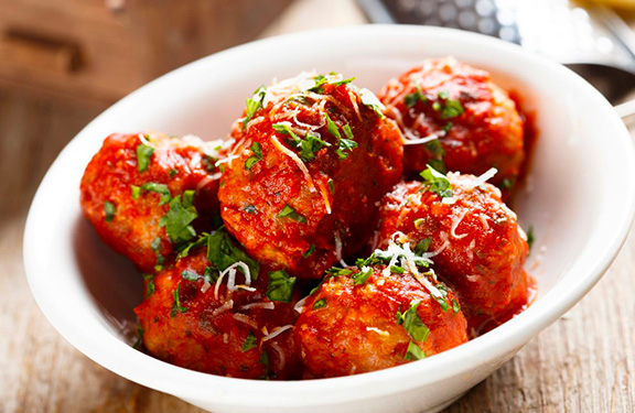 des boulettes de veau dans une assiette avec de la sauce tomate