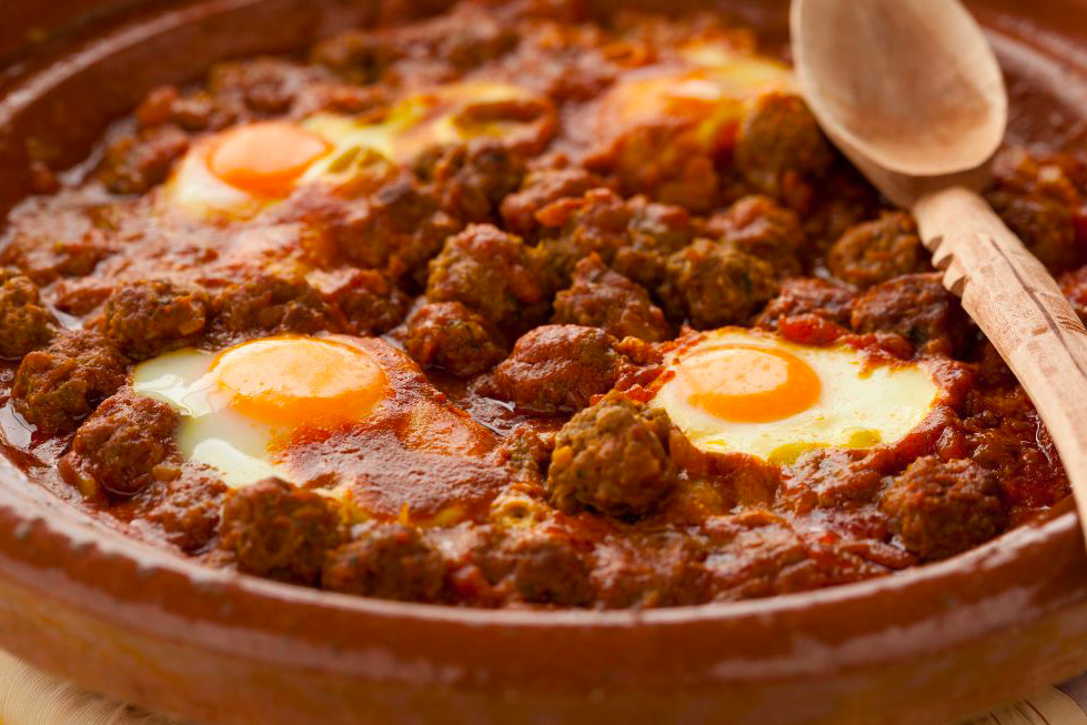 Un chakchouka dans un plat en terre avec des boulettes de kefta