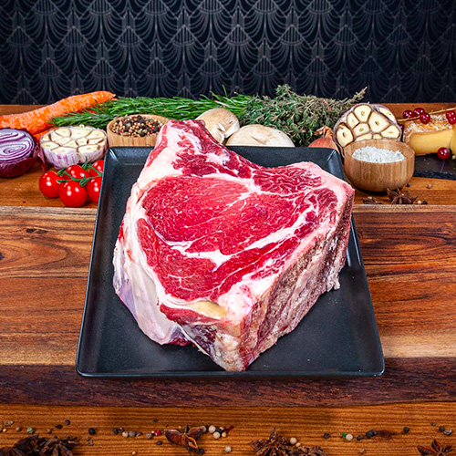 Une côte de boeuf charolaise crue présentée dans une assiette noire