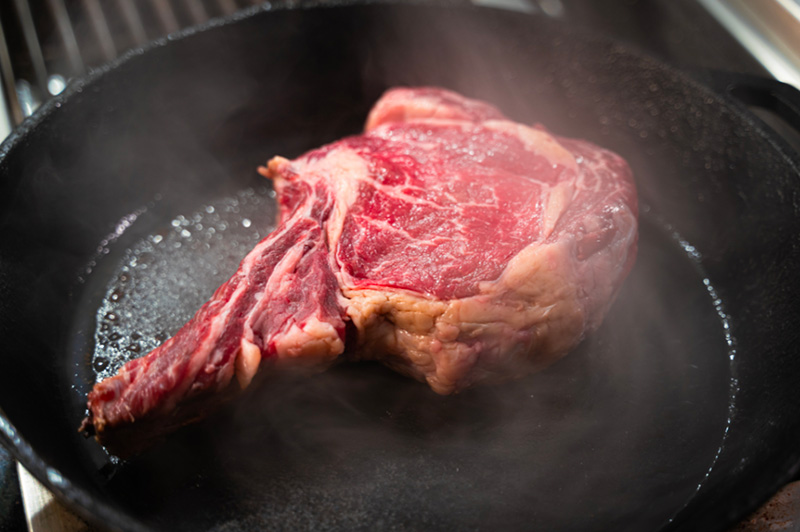 Une côte de boeuf crue dans une poêle en fonte