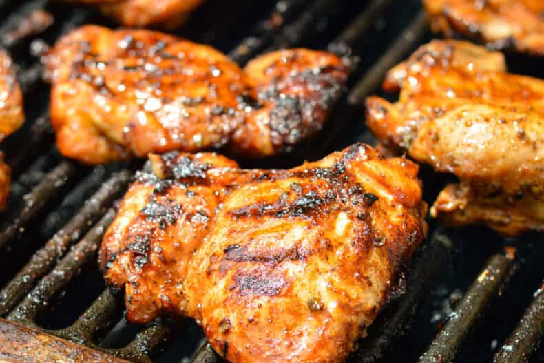 3 cuisses de poulets désossées en train de cuie sur une grille de barbecue