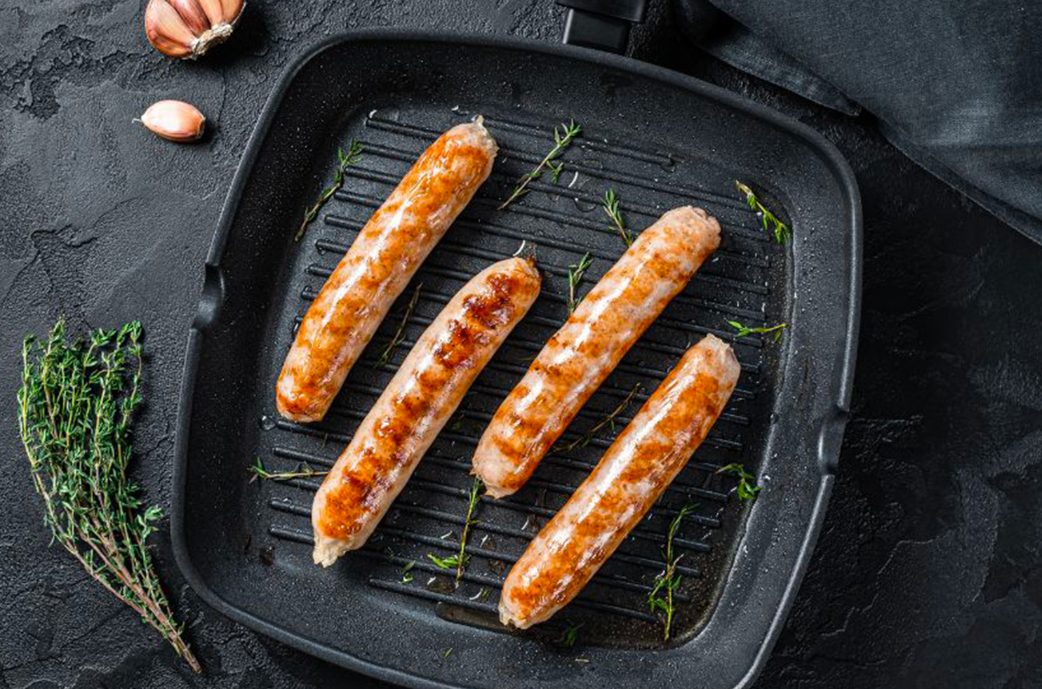 Des saucisses qui cuisent à la poêle