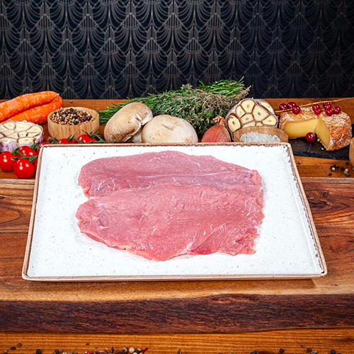 Deux escalopes de veau crues déposées dans une assiette