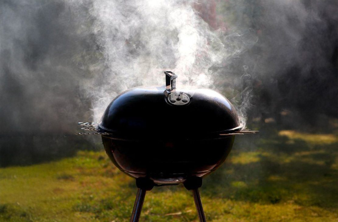 un barbecue fermé avec de la viande qui fume