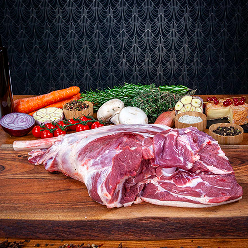 Un gigot d'agneau cru placé sur une planche en bois