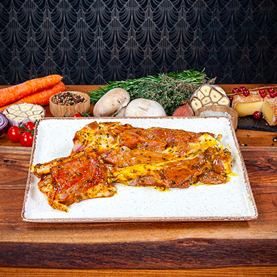 De la viande de veau marinée présentée sur une planche en bois