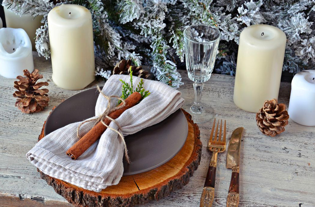 une table de noel décorée avec des assiettes grise et des rondins de bois
