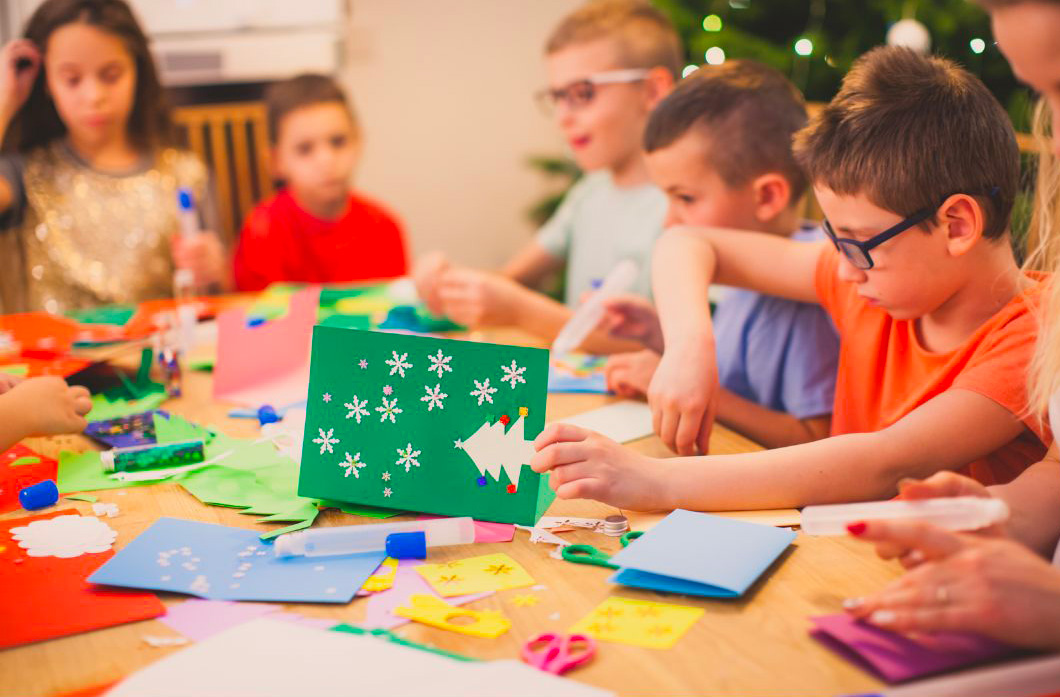 Des enfants qui font des collages sur une table avec des décorationd de Noël