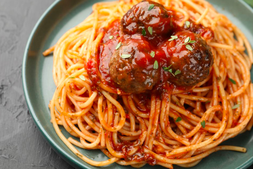 des spaghettis dans une assiette avec une sauce tomates et des boulettes de kefta
