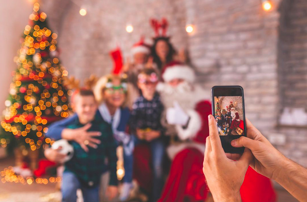 Des gens qui se prennent en photo lors du soir de noel devant le sapin