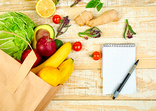 Des fruits et légumes dans un sac en papier avec une liste de courses