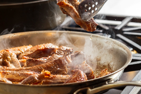 Une poêle en acier qui contient des morceaux de viande