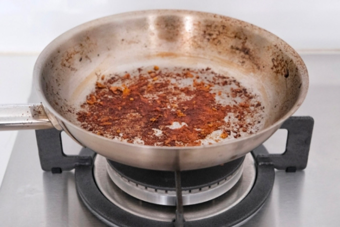 Une poêle en inox dans laquelle il reste des sucs de cuisson