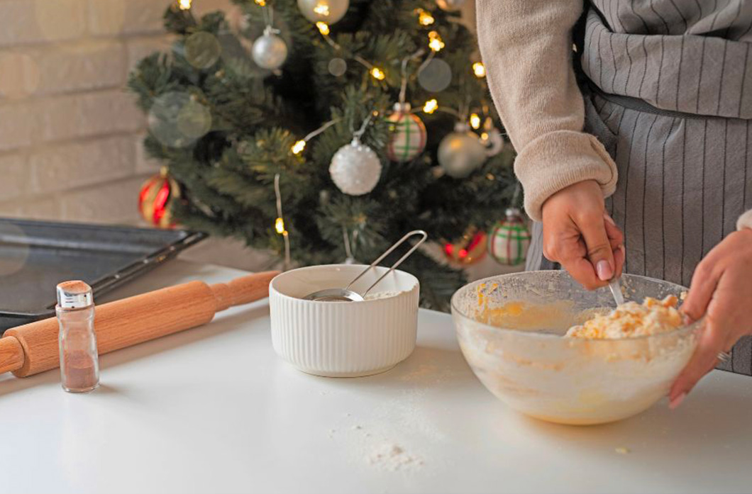 Une femme qui prépare un gateau de noel avec un fouet et un saladier