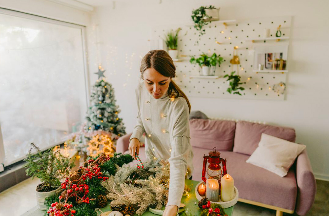 Une femme qui prépare une table de noel avec des branches de sapin