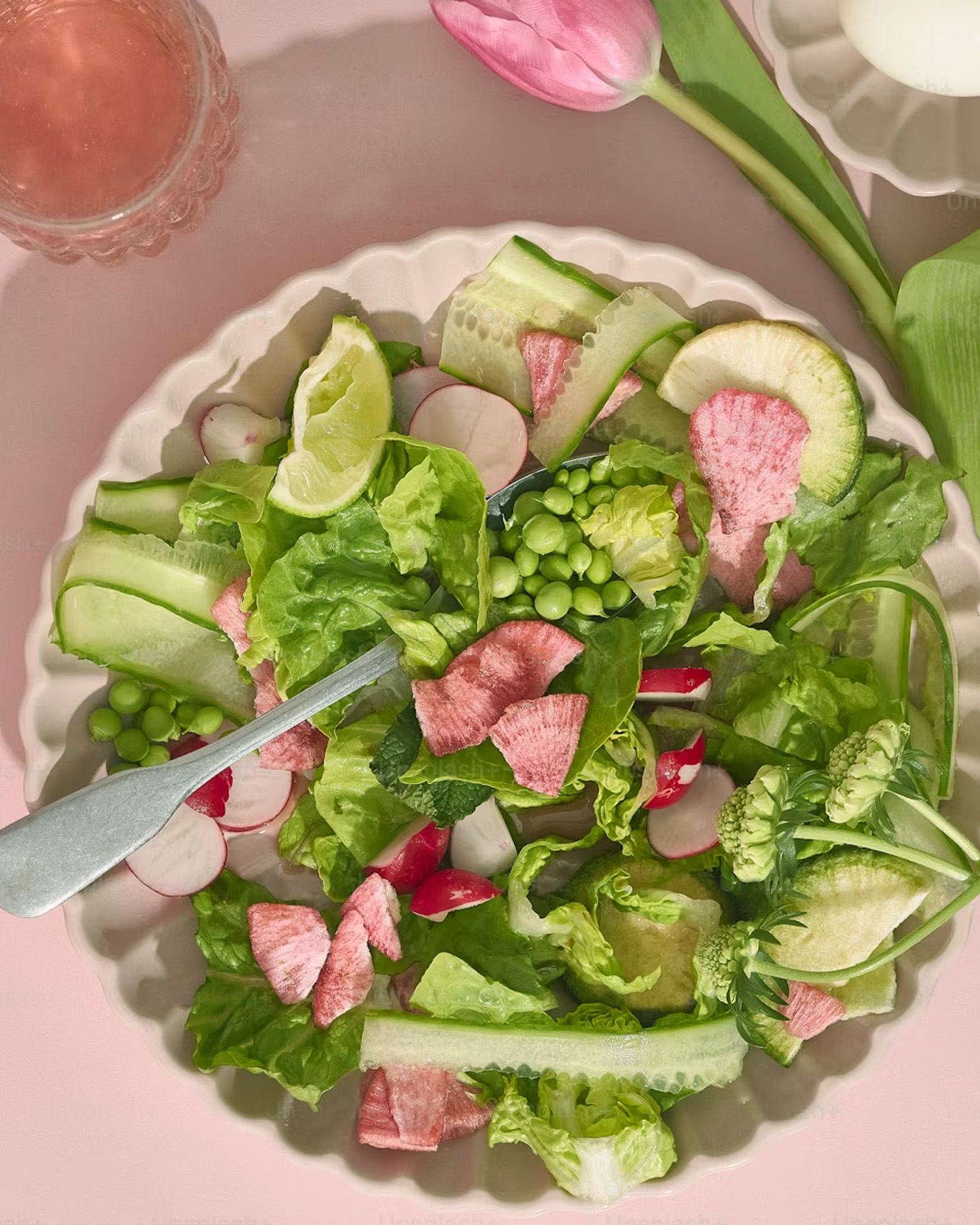 Une salade composée dans une assiette avec des petis pois, radis et concombres