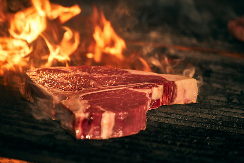 Un t-bone de boeuf mature en train de cuire sur une grille de barbecue