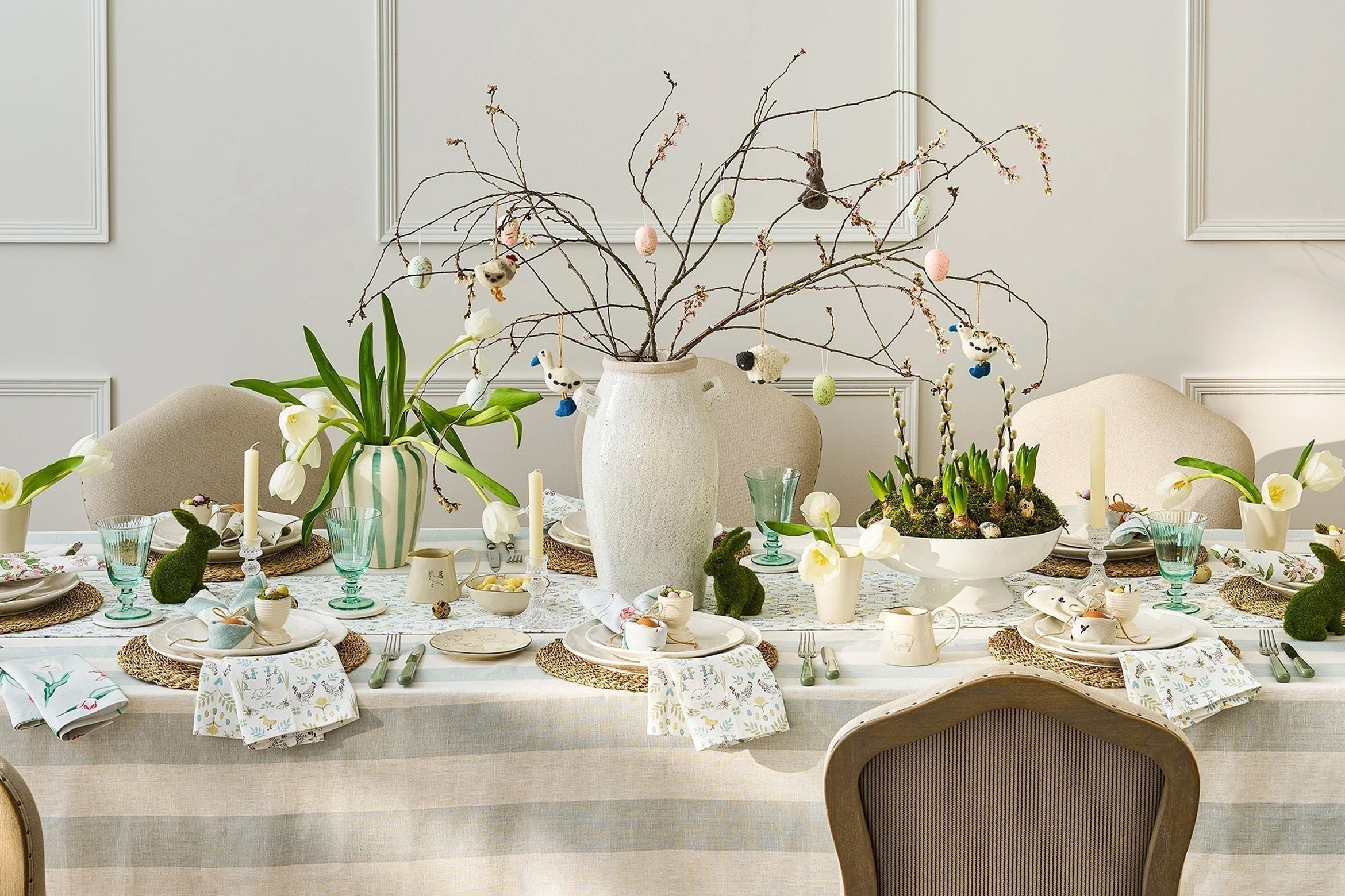 Une table de pâques décorée avec une nappe blanche à rayure et des fleurs