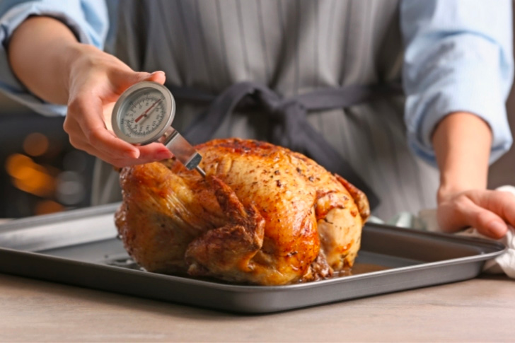 Une personne qui enfonce une onde dans un poulet rôti