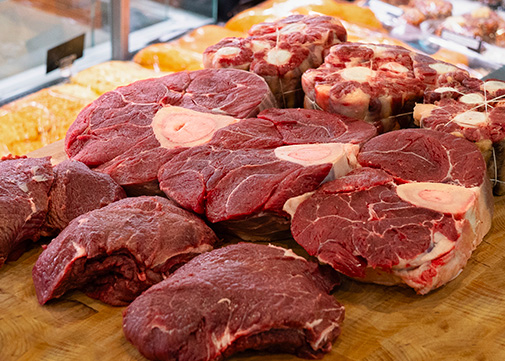 Des moreaux de jarret de boeuf, joeu de boeuf et queue de boeuf sur un plan de travail dans une boucherie