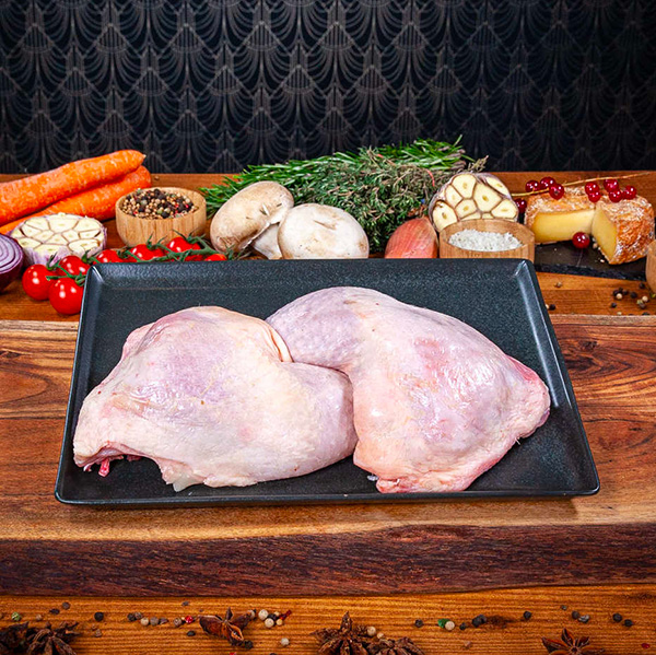 2 cuisses de poulet crues posées sur une planche en bois