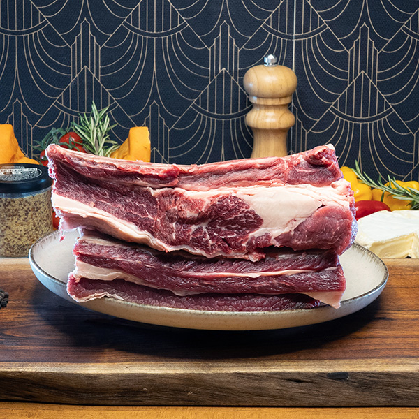 deux pièces de ribs de boeuf crus posées sur une planche en bois