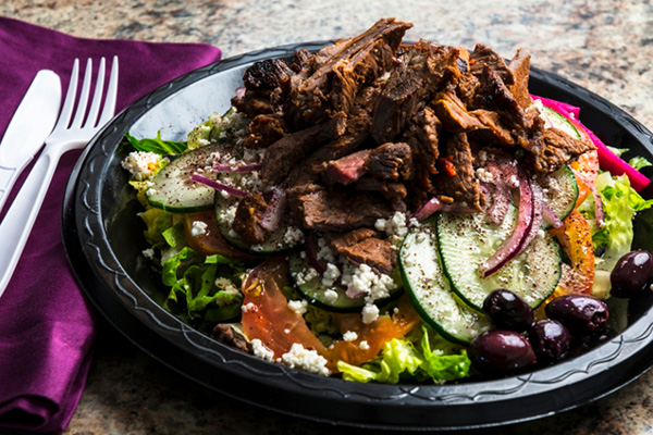 Du gigot d'agneau rôti façon shawarma servi dans une assiette avec une sauce menthe