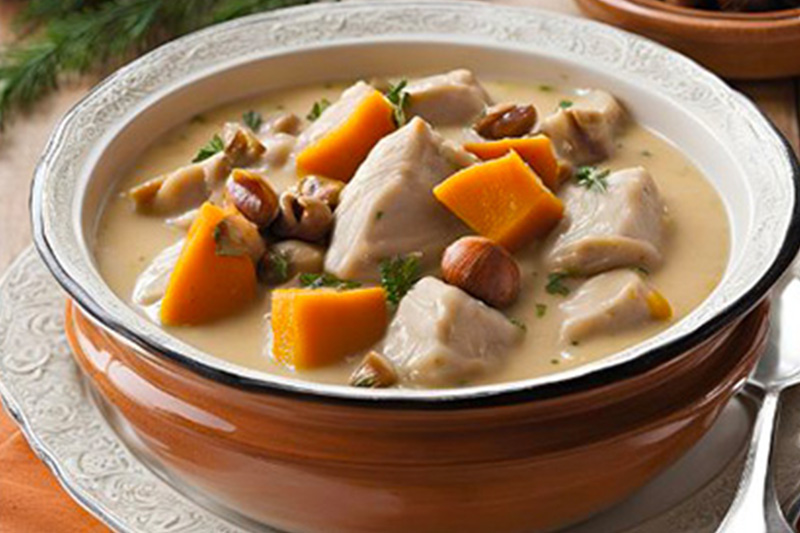 Une blanquette de dinde avec du potiron et des marrons dans une assiette