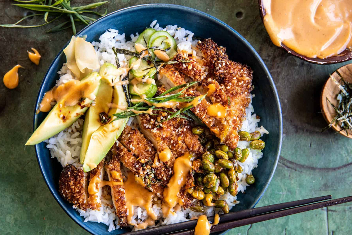 Un bowl de poulet pané acoompagné de riz et concombre