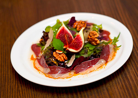 Une salade à base de carpaccio de canard avec des figues, de la roquette et des noix