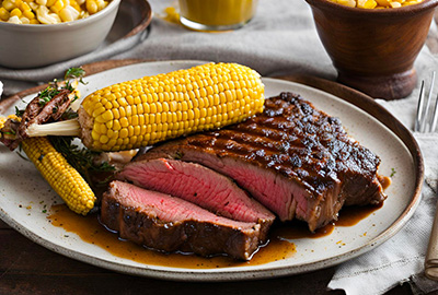 Une côte de boeuf sur une assiette avec un épis de maïs