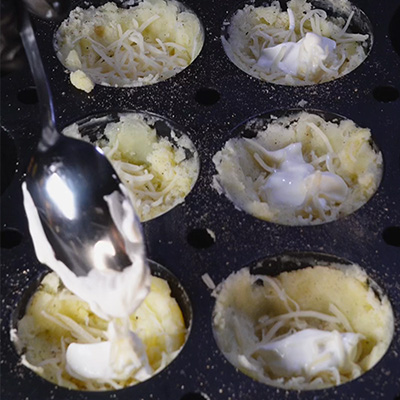 Une main qui met de la crème dans un moule à muffin