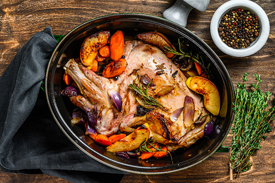 Une épaule d'agneau confite dans une cocotte accomapgné des légumes et aromates
