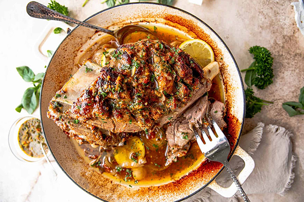 Uen épaule d'agneau confite avec un jus aux agrumes dans une cocotte en fonte