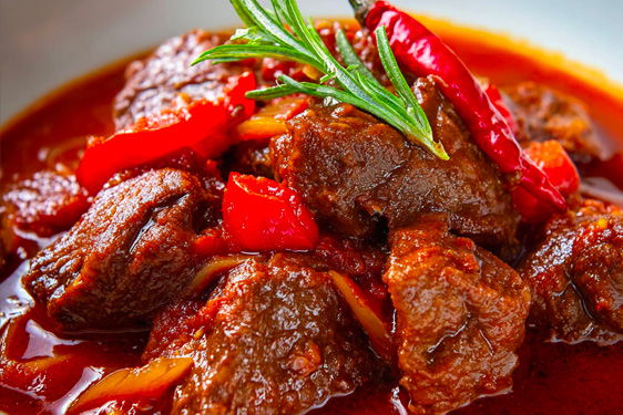 une assiette contenant un plat de joue de boeuf à la sauce tomate avec des piments