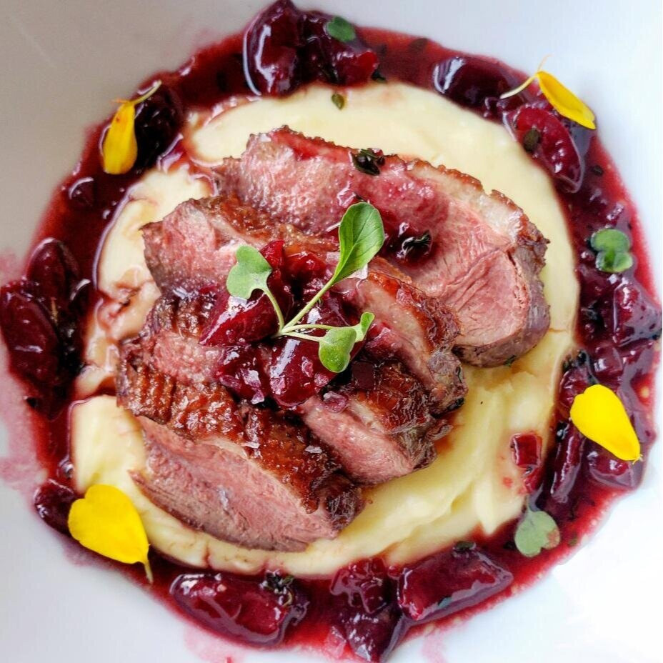 Des tranches de magret de canard dans une assiette avec leur sauce à la cerise