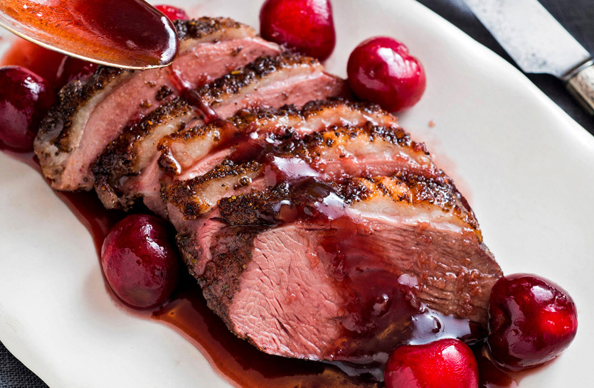 Un magret de canard tranché avec sa sauce aux cerises