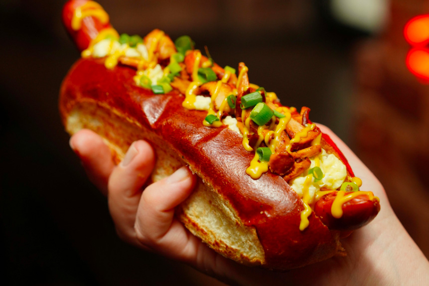 Une main qui tient un hot dog à la merguez