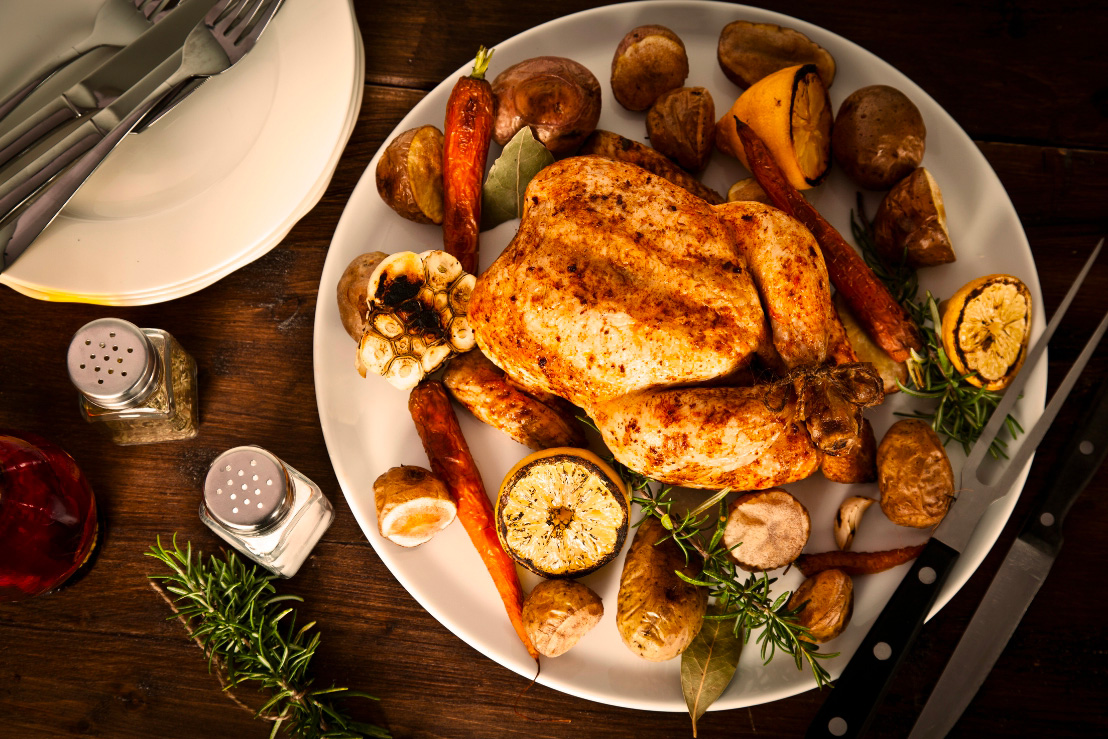 Une poulet rôti cuit sevi dans une assiette avec du citron et de l'ail