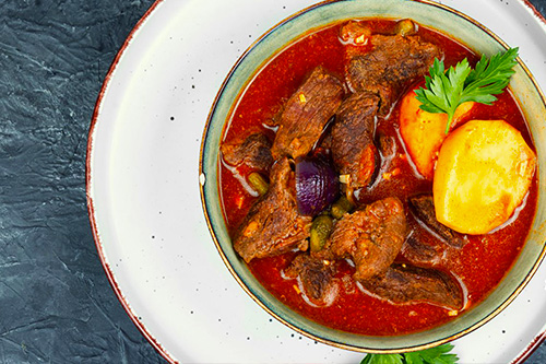 une assiette qui contient un goulash revisé à la viande boeuf et sauce