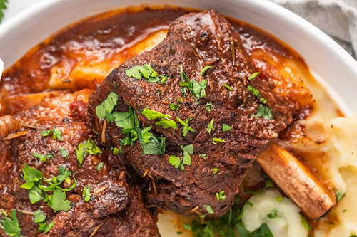 Des ribs de boeuf en train de confire dans une cocotte