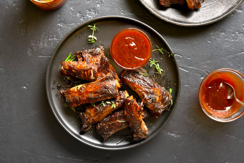 des ribs de veau cuits au barbecue présentés dans une assiette noire