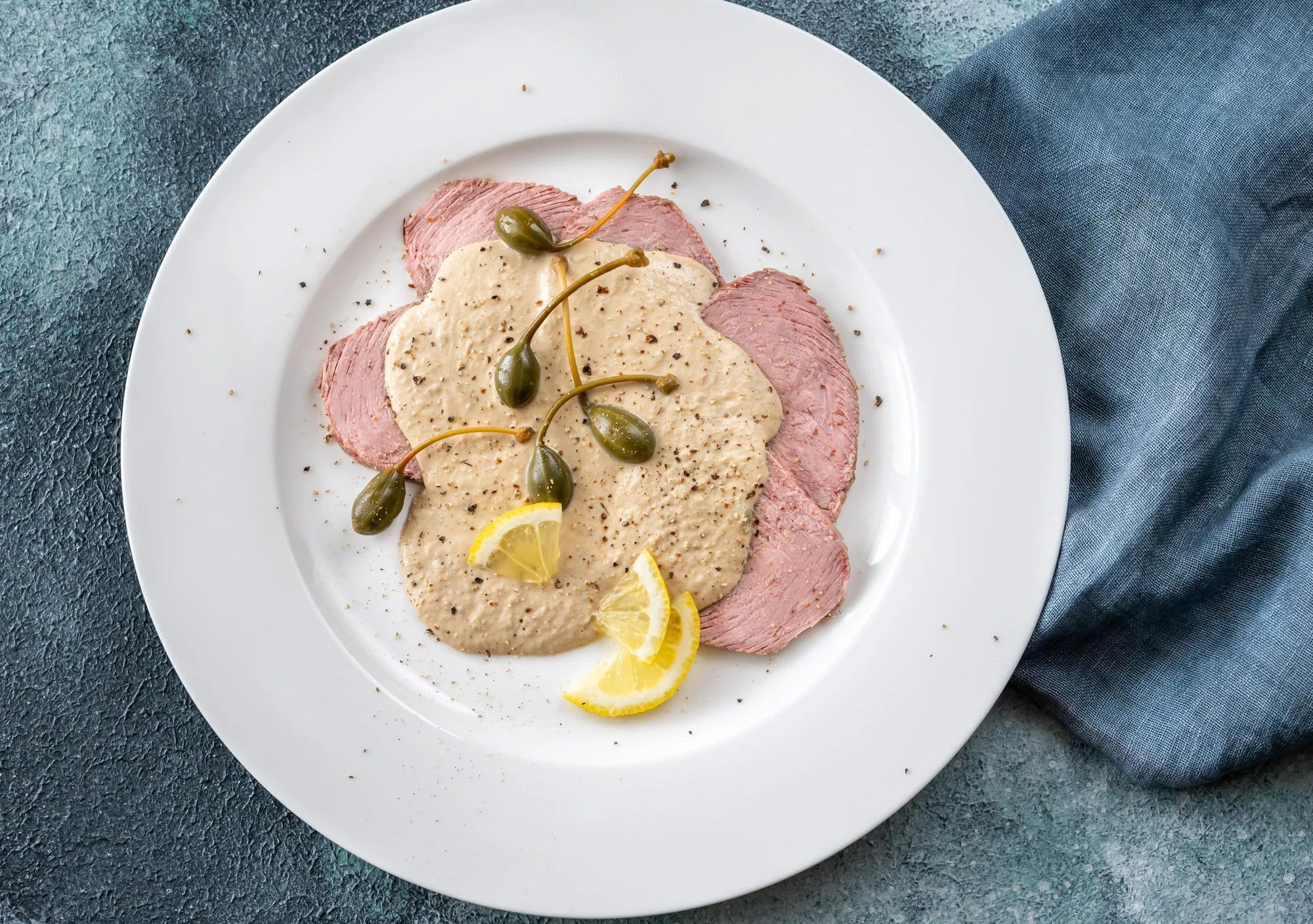 Un rôti de veau sauce tonnato tranché dans une assiette