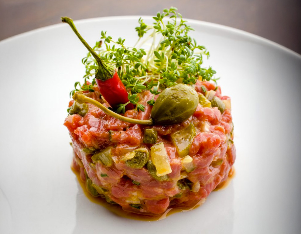 un tartare de boeuf à l'ail des ours dans une assiette blanche