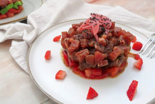Un tartare de boeuf et fraises dressé sur une assiette blanche