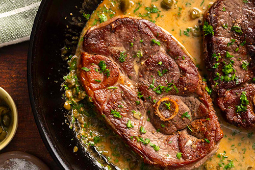 une tranche de gigot d'agneau mijotée avec une sauce et des légumes