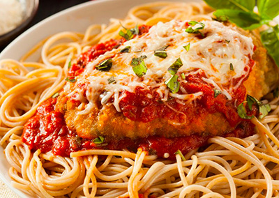 Une escalope de veau surmontée de spaghettis et de sauce tomate dans une assiette